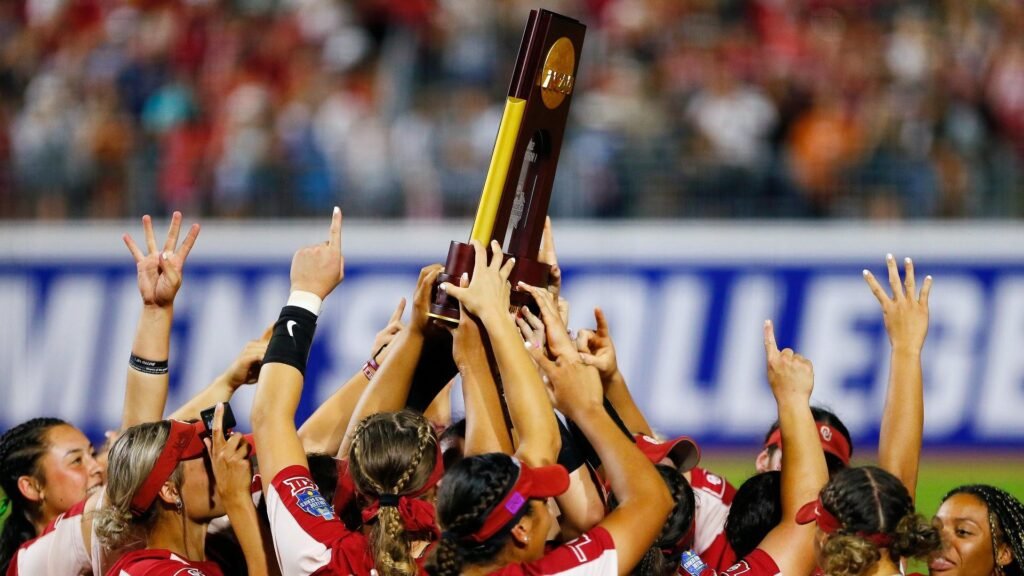 "NCAA softball team holding their trophy"