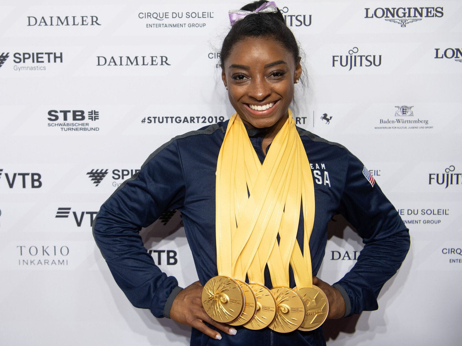 Simone Biles: A Superhuman in Gymnastics! Here's an alt attribute for an image of Simone Biles wearing medals: Simone Biles wearing multiple medals and smiling.